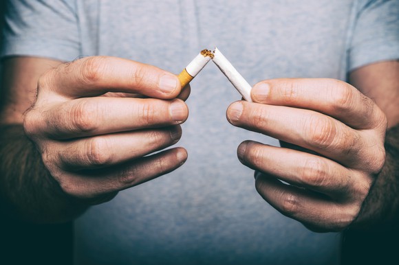 Man breaking cigarette in half.