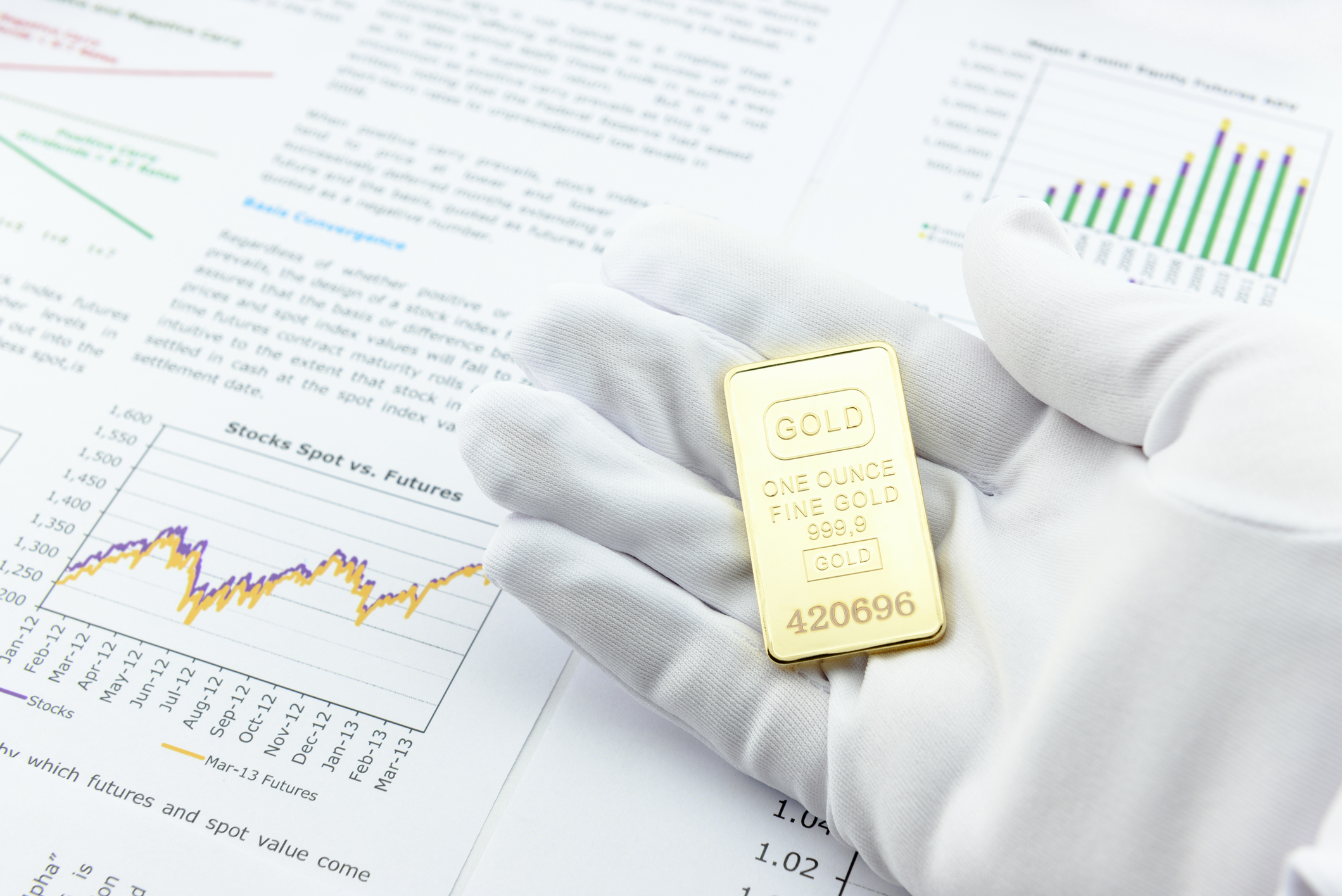 Person in a glove holding a gold ingot with a rising stock chart in the background.