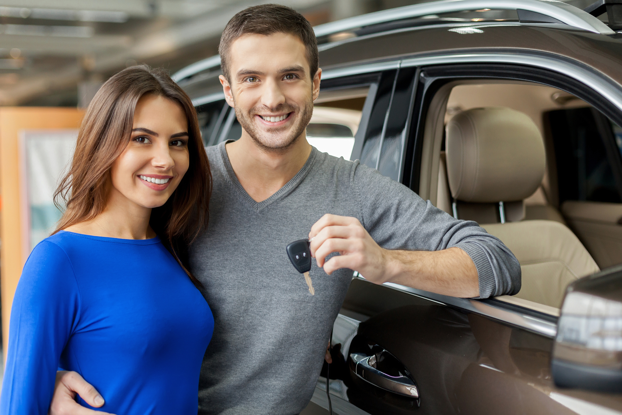 A couple holding keys to a new car
