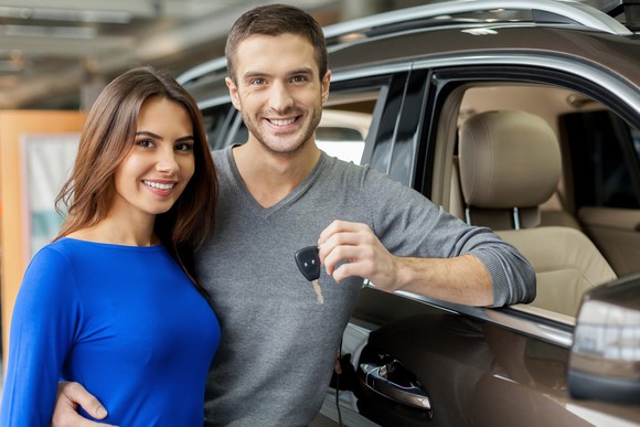 A couple holding keys to a new car