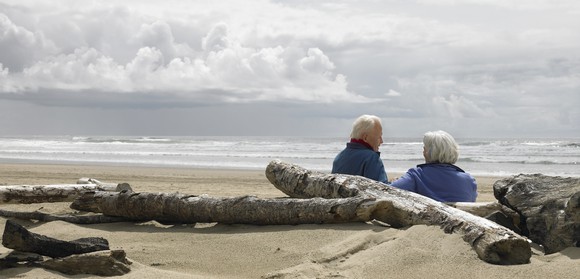 Older couple on a beach with driftwood.