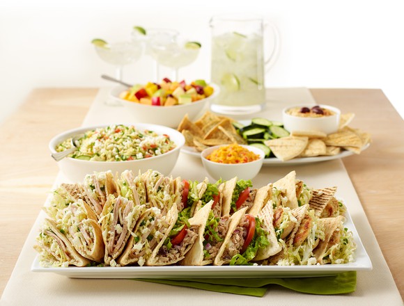 A serving tray with a sampler of Zoe's Kitchen food items.
