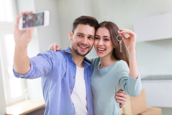 Young couple with keys to their first home.