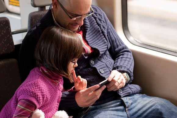 A man and a girl looking at a smartphone.