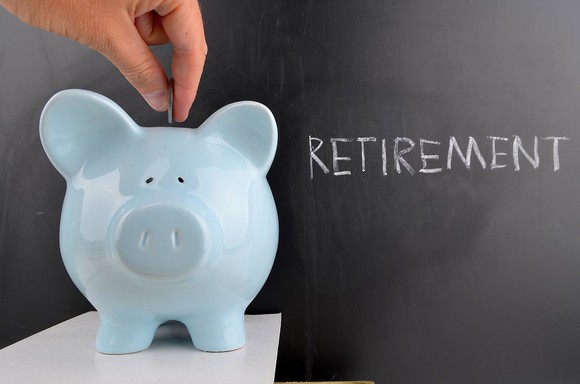 Blue piggy bank in front of the word retirement on a blackboard