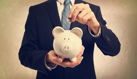 Man in suit putting money in a piggy bank