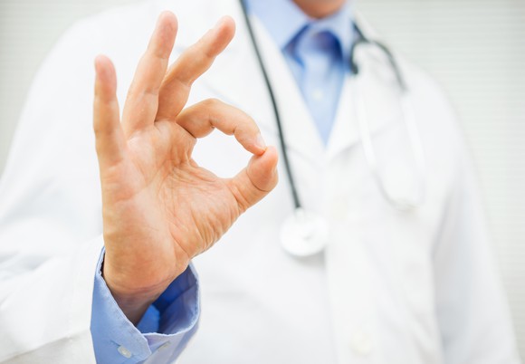 Torso of doctor in jacket making the okay sign with his fingers