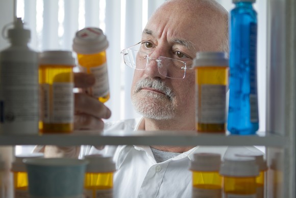 Senior citizen examining pills in his medicine cabinet