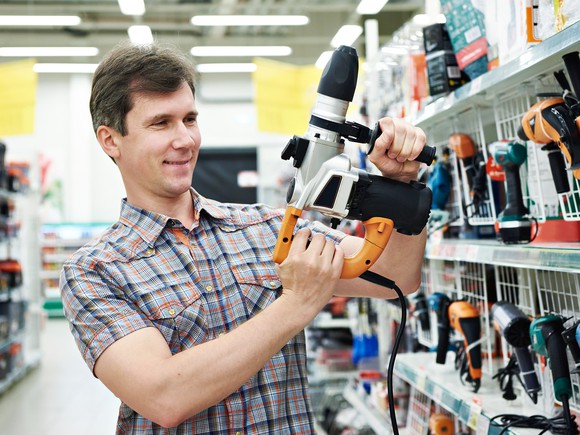 A customer examining a drill in a home improvement store.