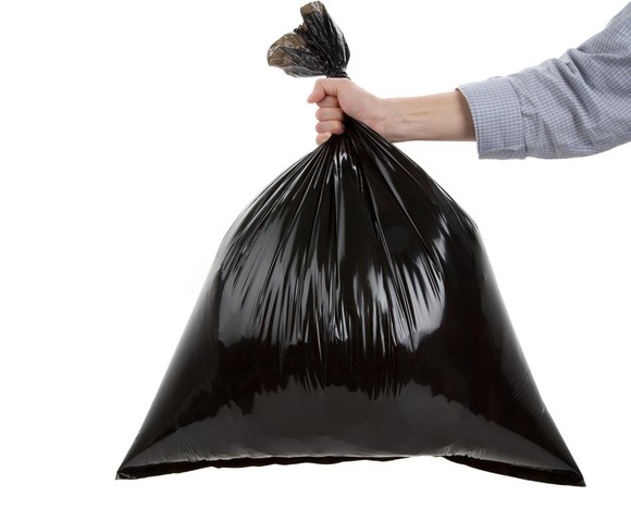 Hand holding black trash bag.