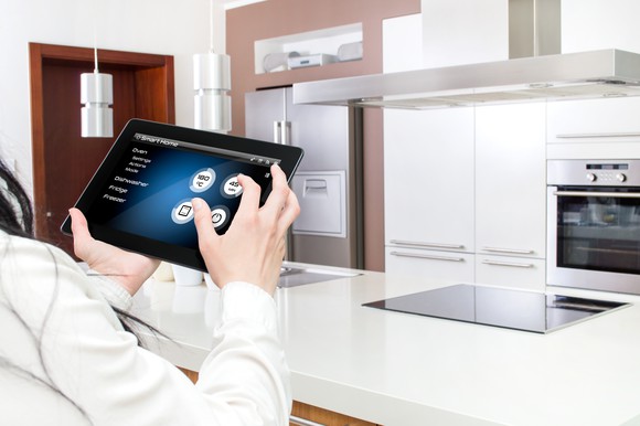 A women controls a smart kitchen using an iPad.