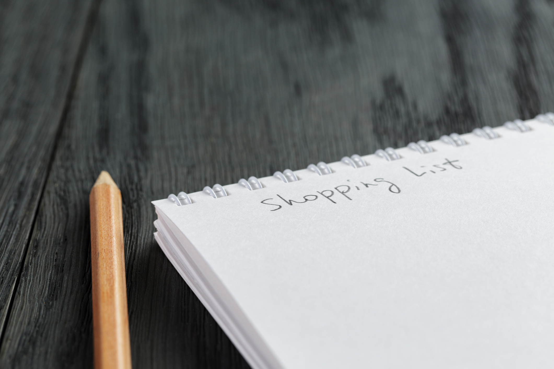 a pencil next to a note pad, with "shopping list" written on it.
