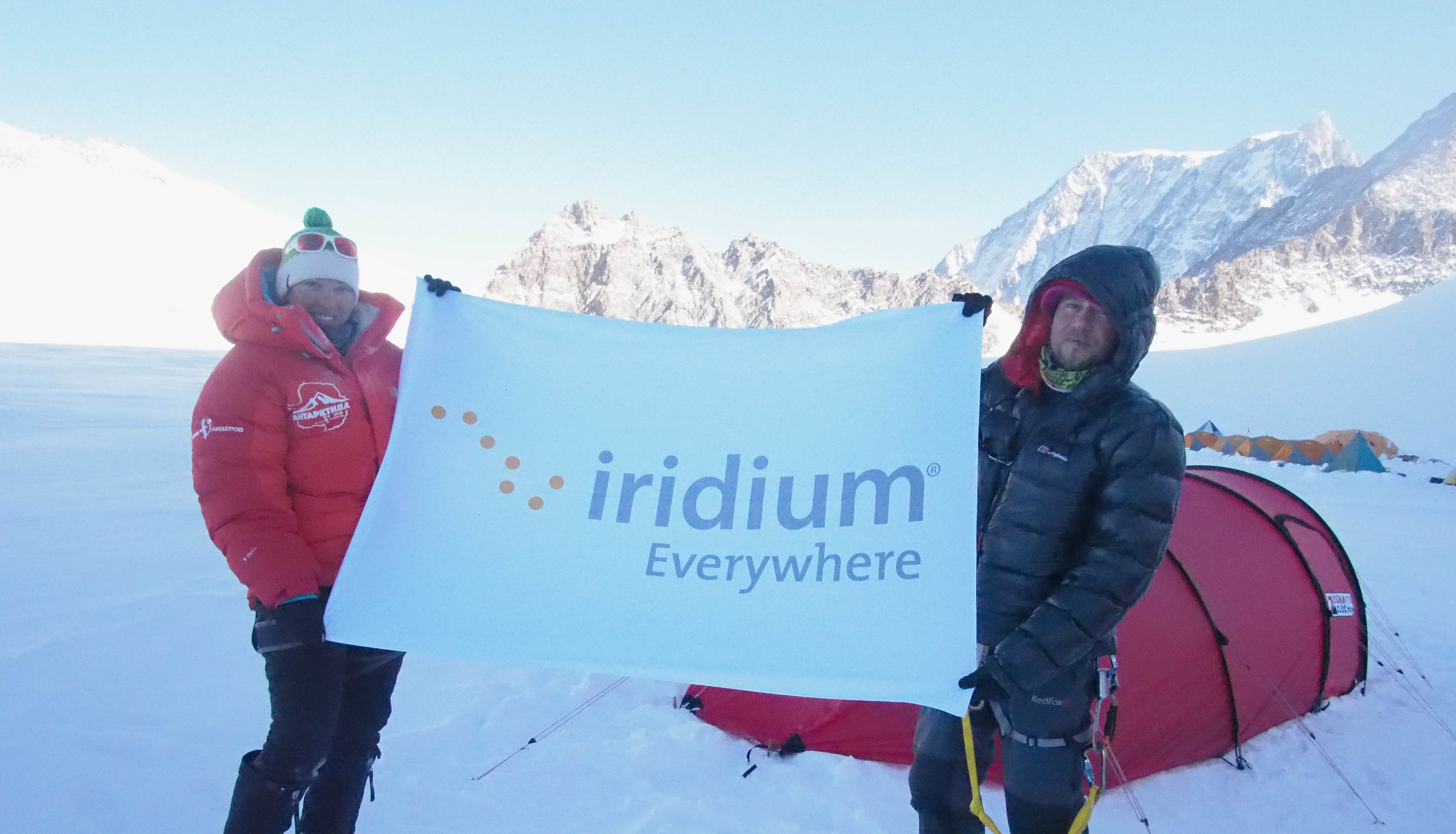 Two people in Arctic conditions holding Iridium sign.