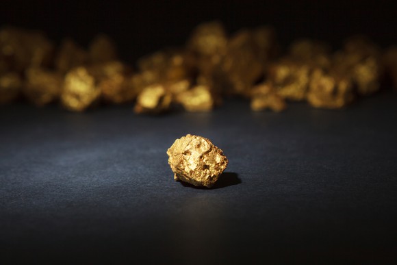 Gold nuggets sitting on a dark table.