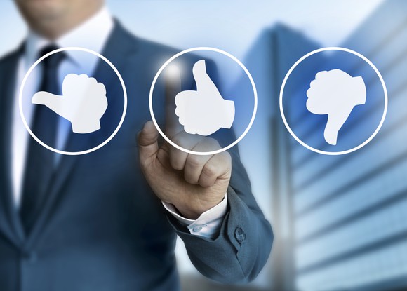 A business man points at a thumbs up, rather than thumbs down or sideways.