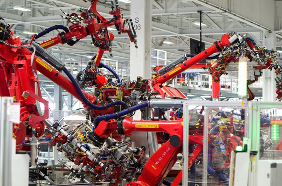 Model X central assembly point in Tesla's car factory shows robotic arms assembling the SUV.