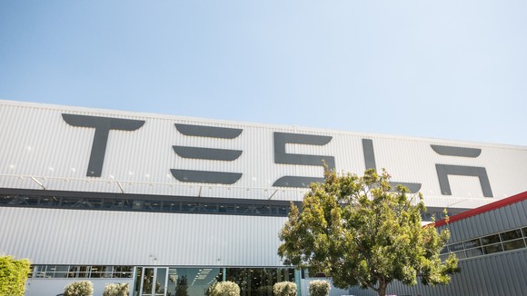 Tesla car factory with "Tesla" in big letters on the outside of the factory.