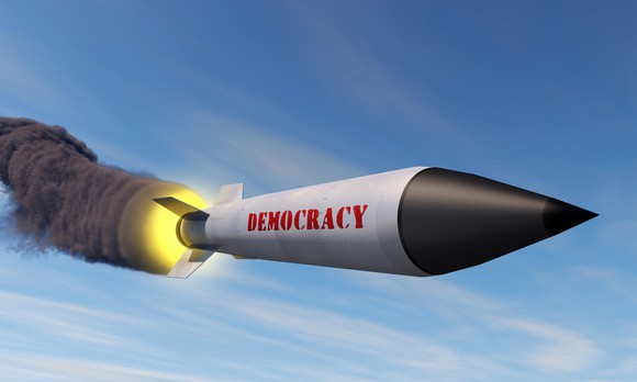 Rocket labeled "Democracy" blazing a trail of smoke across the sky.