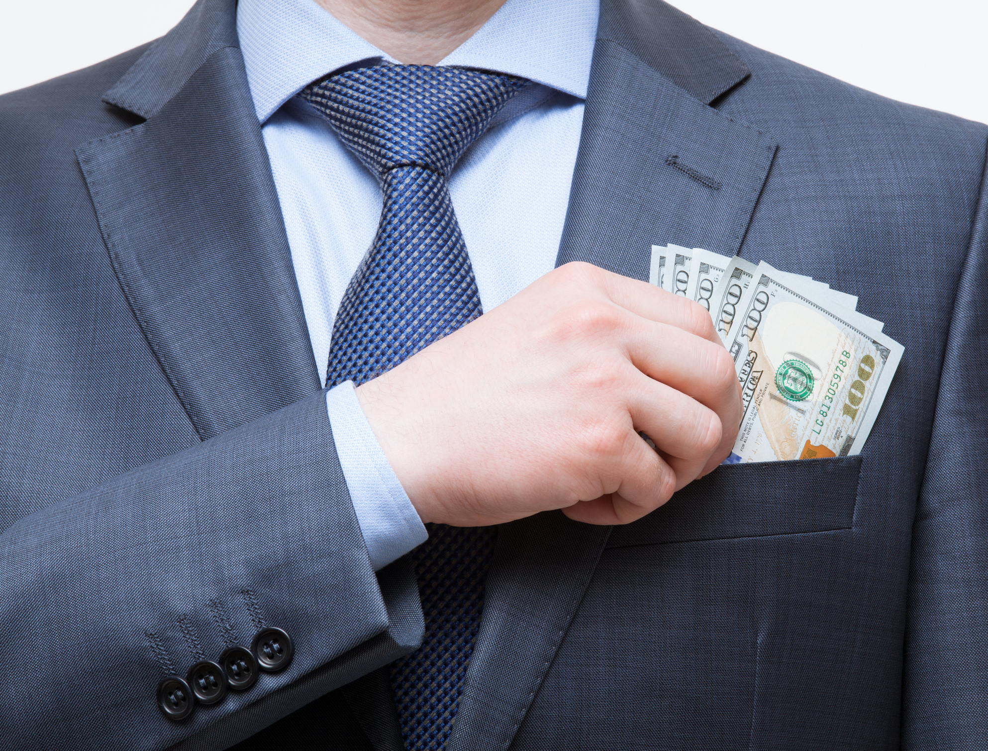 Wealthy businessman putting cash in his front pocket.