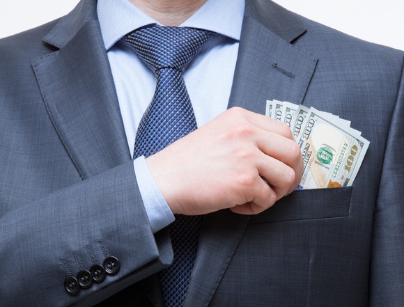 Wealthy businessman putting cash in his front pocket.