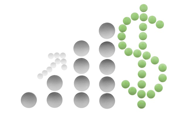 Pills laid out to form a dollar sign and a graph that represents increasing sales.