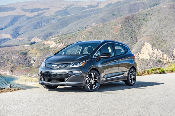A black Chevy Bolt with mountains in the background.