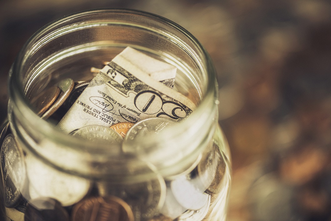 Glass jar filled with coins and currency.