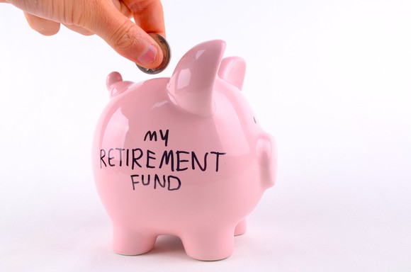 Person putting money into a pink piggy bank labeled "My Retirement Fund"