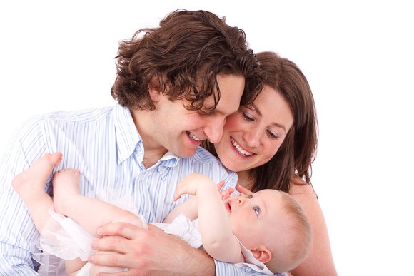 A man holding a baby, flanked by his spouse.