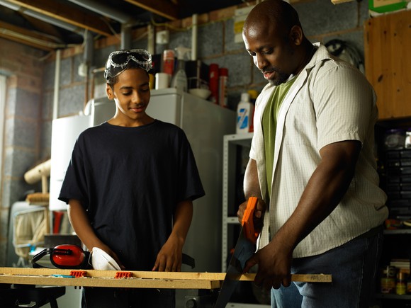 Father teaching his teenage son about carpentry.
