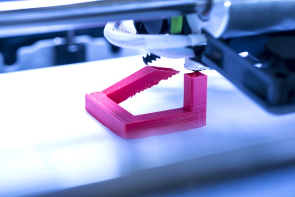 Close-up of a 3D printer printing a fuchsia-colored object.