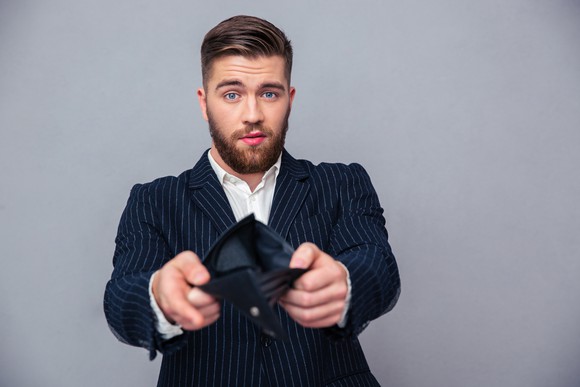 Businessman in a suit holding up an empty wallet.
