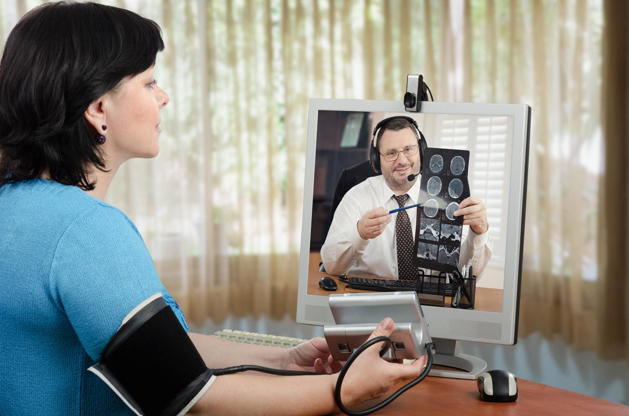 Female patient taking blood pressure in videoconference with doctor
