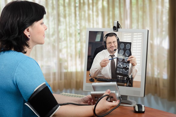 Female patient taking blood pressure in videoconference with doctor
