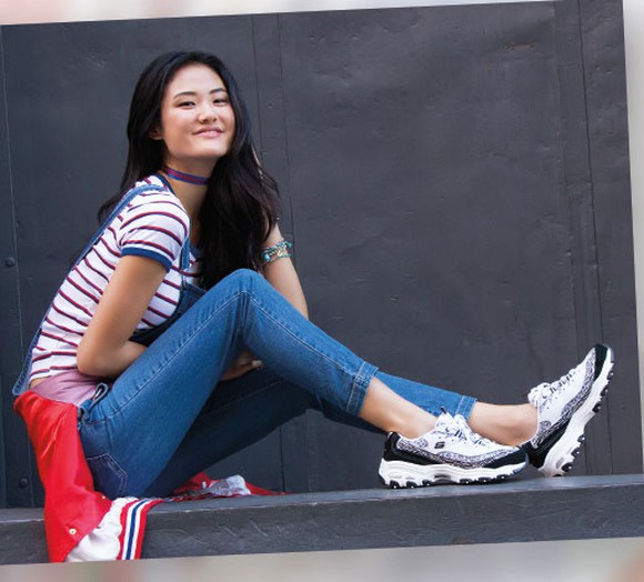 A young woman wearing Skechers sneakers.