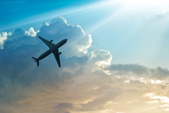 An airplane soaring past clouds in the background