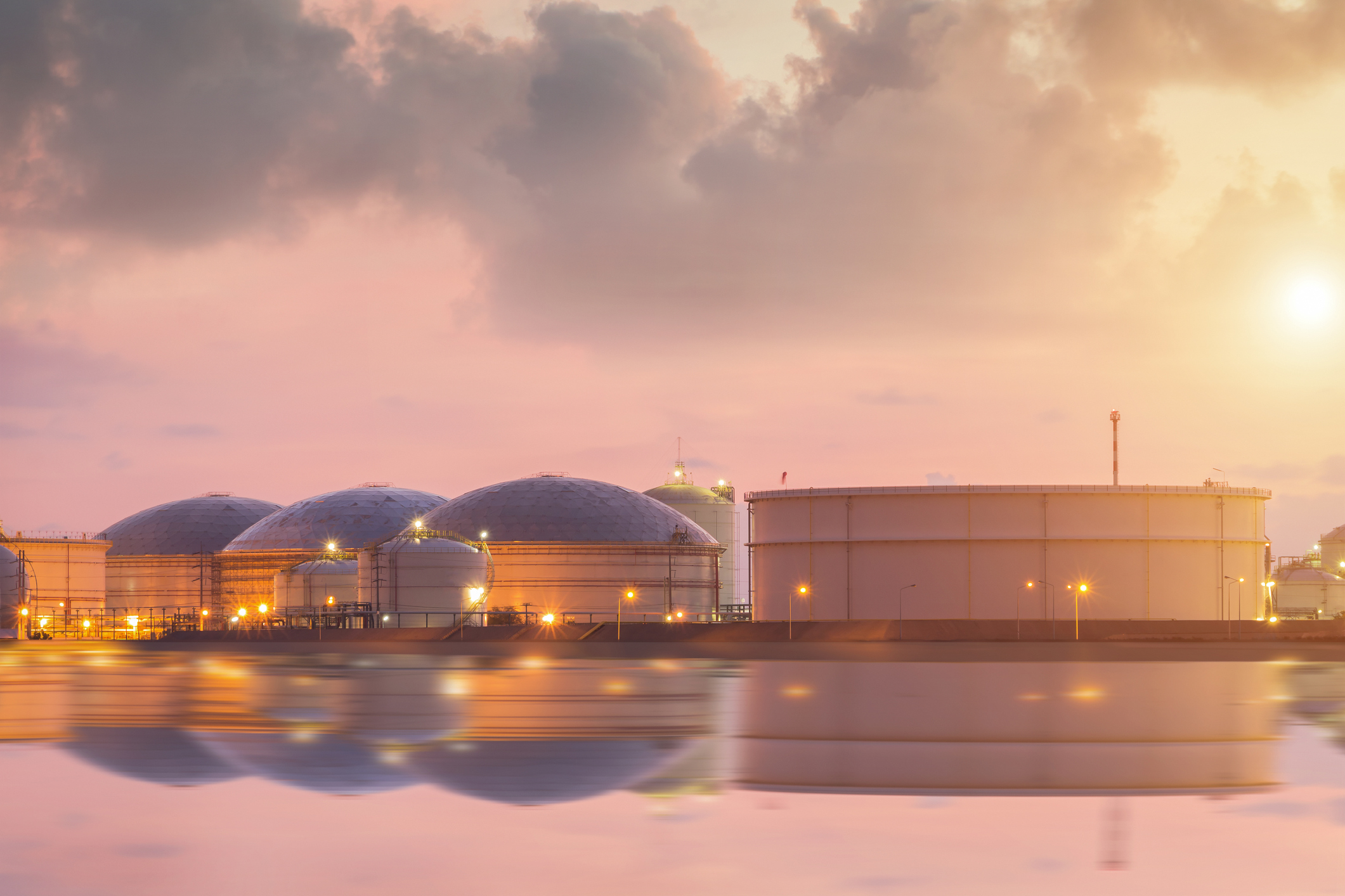 Petroleum product storage tanks reflecting on the water.