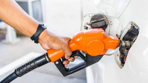 Hand holding a fuel pump into a white car