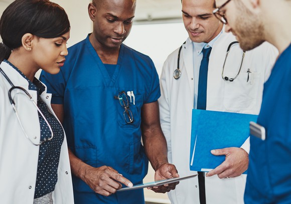 Four doctors looking at informational charts.