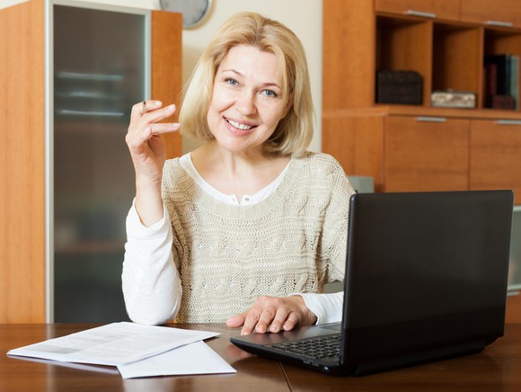 A smiling woman examining financial documents.