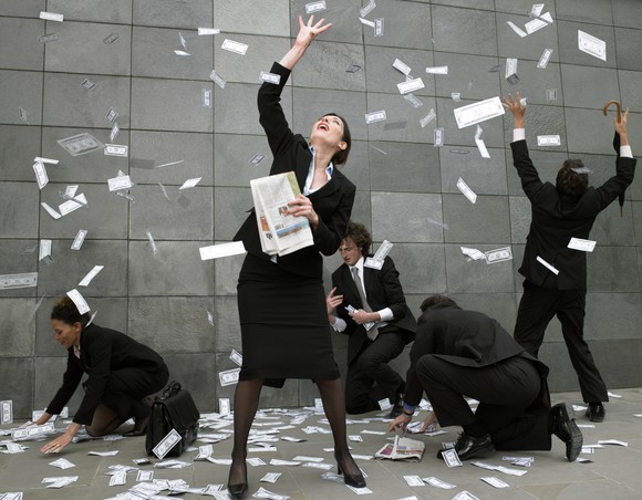 People grabbing paper money falling from the sky.