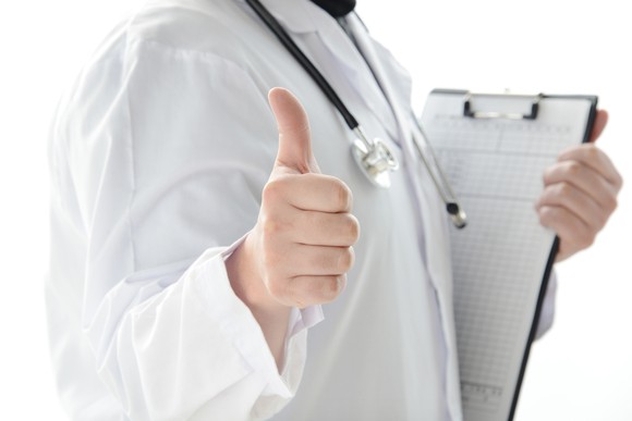 Doctor with a clipboard giving the thumbs-up sign