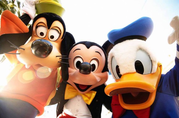 Goofy, Mickey Mouse, and Donald Duck posing for a photo at Disneyland.