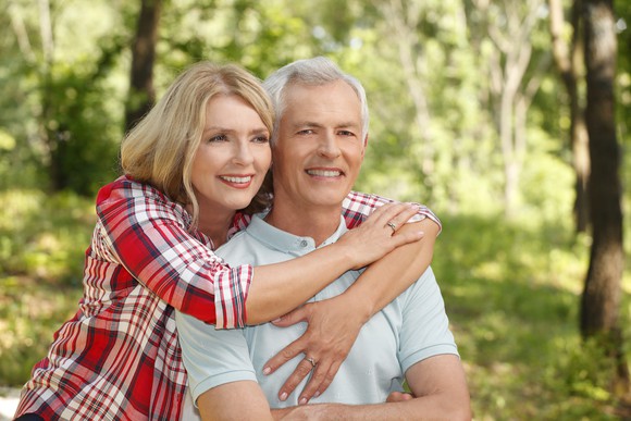 A woman hugging her husband while sitting outdoors and smiling