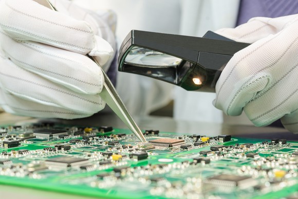 Assembly worker soldering circuits on a semiconductor.