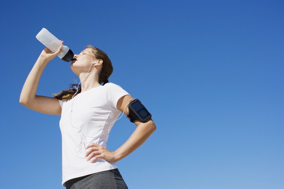 A jogger drinking out of a water bottle.