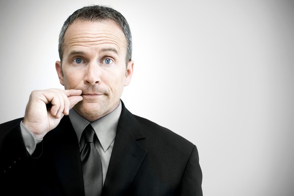 Businessman with hands in from of lips indicating secrecy/quiet.