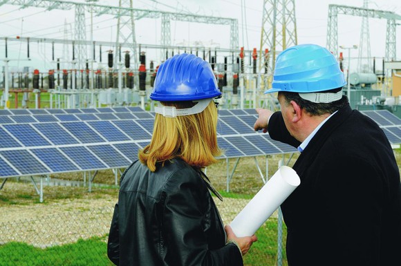 Man and woman in hard hats overlooking work site.