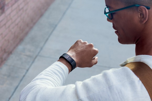 Man in glasses looking at his Fitbit Charge 2 on his wrist.