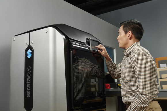 Worker operating a 3D printing machine.